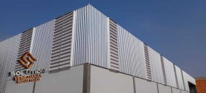 Fachada industrial moderna com venezianas e painéis de policarbonato para ventilação e iluminação natural.
