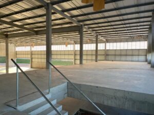 Vista em perspectiva da lateral do galpão OPUSPAC em Louveira, exibindo a longa linha de venezianas Solution. A imagem destaca a continuidade do policarbonato alveolar branco e a robustez da estrutura metálica instalada.