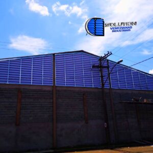 Vista panorâmica de diversos galpões industriais da Sinner Empreendimentos em Cravinhos, SP, equipados com sistema completo de venezianas industriais Solution. A imagem destaca a padronização e a escala da instalação em toda a extensão das fachadas.