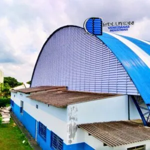 Venezianas industriais Solution em policarbonato alveolar branco leitoso translúcido, fabricadas em formato de arco para fechamento lateral de ginásio poliesportivo, destacando a difusão de luz natural.