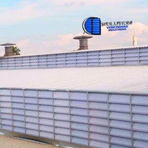 Lanternim de galpão industrial equipado com venezianas Solution em policarbonato branco translúcido, destacando a exaustão térmica e iluminação zenital difusa.