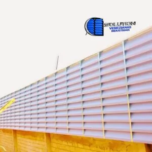 Fachada industrial com venezianas Solution em PVC branco leitoso, destacando as aletas opacas que garantem ventilação permanente e privacidade interna