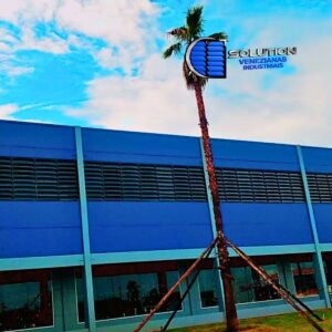 Fachada industrial com venezianas Solution em policarbonato alveolar fumê translúcido, destacando o controle de brilho solar e a ventilação permanente.