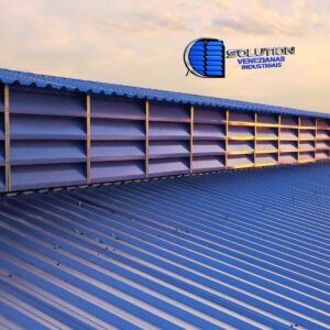 A escolha do policarbonato branco translúcido em vez de materiais opacos ou totalmente incolores oferece uma vantagem luminosa única: a difusão de luz zenital. As lâminas filtram a radiação direta, transformando o lanternim em uma claraboia linear que distribui a luminosidade de forma homogênea sobre as linhas de produção, eliminando o ofuscamento e reduzindo a temperatura radiante. Além disso, o policarbonato possui tratamento contra raios UV, garantindo que as aletas mantenham sua integridade estrutural e estética por muito mais tempo.