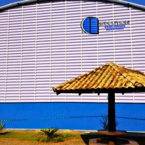 🖼️ Texto Alternativo"Fachada de ginásio poliesportivo com venezianas Solution em policarbonato alveolar branco leitoso, fabricadas com curvatura em arco para acompanhar o design da cobertura abaulada