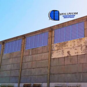 Fachada de galpão industrial com venezianas Solution em PVC branco leitoso. A imagem destaca as aletas de PVC fixas, que proporcionam ventilação natural permanente e uma iluminação difusa e agradável em toda a área fabril.